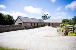 an external view of a stone building with a driveway at Sharlands Farm Holiday Cottages in Bude
