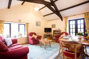 a living room with red chairs and a table at Sharlands Farm Holiday Cottages in Bude