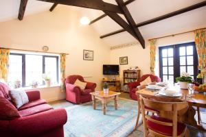 ein Wohnzimmer mit roten Stühlen und einem Tisch in der Unterkunft Sharlands Farm Holiday Cottages in Bude