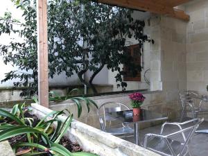 un patio con mesa, sillas y un árbol en Monterussi Bed and Breakfast, en Cavallino di Lecce