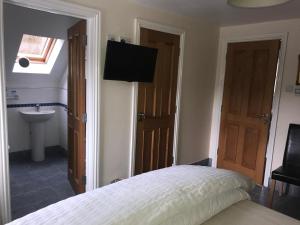 a bedroom with a bed and a sink and a television at Riverside Cottage B&B in Cladich
