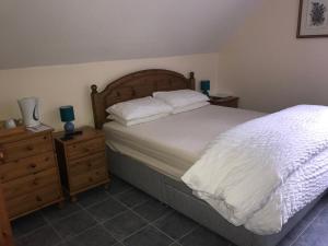 um quarto com uma cama com duas mesas de cabeceira e uma cama com lençóis brancos em Riverside Cottage B&B em Cladich