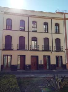 duży budynek z brązowymi drzwiami i oknami w obiekcie Suites Jeronimo de Cordoba w Sewilli
