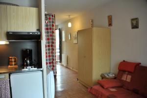 a kitchen and a living room with a couch and a refrigerator at location 4 pers Angélique t 2 résidence les bords du lac lac in Le Lauzet-Ubaye