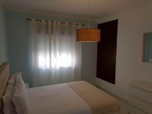 ein Schlafzimmer mit einem weißen Bett und einem Fenster in der Unterkunft Casa da Praia in Armação de Pêra