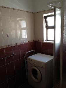 a bathroom with a washing machine and a window at Casa da Praia in Armação de Pêra