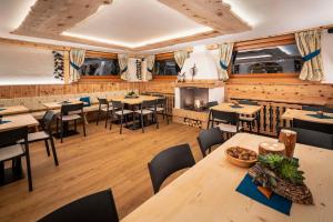 un ristorante con tavoli, sedie e un camino di Hotel Ciasa Lorenzi a Cortina dʼAmpezzo