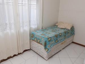 een klein bed in een kamer met een gordijn bij Praia da Ilhota, lado de Baneário Camboriú in Itapema