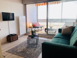 a living room with a green couch and a large window at STUDIO FACE MER PORNICHET – VUE BAIE DE LA BAULE in Pornichet +4 photos