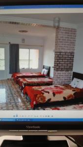 Zimmer mit 3 Betten und einem TV in der Unterkunft Auberge BAB IMOUZER in Tagherat Anekrim