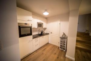 a kitchen with white cabinets and wooden floors at Duenenschloss in Westerland (Sylt)