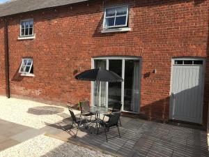 een patio met een tafel en stoelen en een parasol bij Rolling Mill, Wolds Way Holiday Cottages, 2 Bed, 1st floor in Cottingham