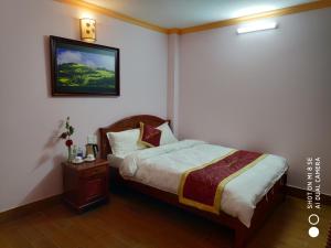 1 dormitorio con 1 cama y una foto en la pared en Quoc Thai Sapa Hotel en Sa Pa