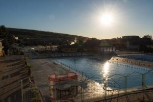 a large swimming pool with the sun in the sky at Apartmany Arcadia in Podhájska
