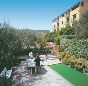 a man sitting on a bench in a garden at Residence Elvira in Diano Marina