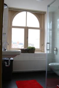 baño con lavabo, ventana y aseo en Het Oude Kantongerecht, en Apeldoorn