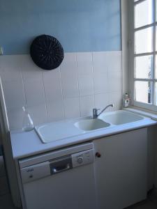 a white kitchen with a sink and a window at FACE A LA MER , L ARTISTE in Ambleteuse