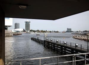 - une vue sur une rivière avec une jetée et des bâtiments dans l'établissement SWEETS - Westerdoksbrug, à Amsterdam