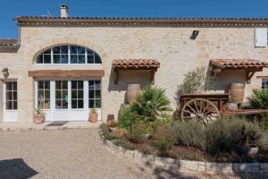 a stone house with a garden in front of it at L'Ilot Vignes in Rauzan