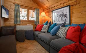 een woonkamer met een grijze bank en kleurrijke kussens bij Chalet Ananas, Hameau des Marmottes in Les Menuires