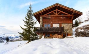 een blokhut met een terras in de sneeuw bij Chalet Ananas, Hameau des Marmottes in Les Menuires