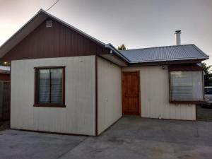 a white and brown house with a garage at Cabaña Centro Pitrufquen in Pitrufquén