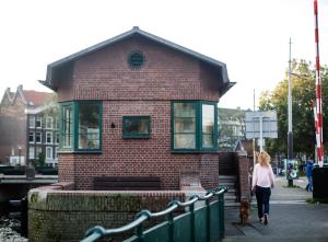 a woman walking a dog in front of a brick building at SWEETS - Kattenslootbrug in Amsterdam +7 photos