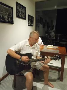 a man sitting in a chair playing a guitar at Lotus Lake Residence in Kandy