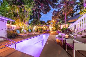 a swimming pool with chairs and a table next to a house at Andrews Inn & Garden Cottages in Key West