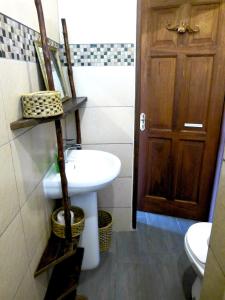 a bathroom with a sink and a toilet and a door at Swahili Oasis in Diani Beach