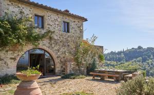 um edifício de pedra com um banco e uma mesa em Casale Sandonatino by VacaVilla em Castellina in Chianti