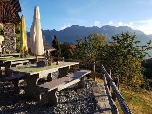 ein Picknicktisch mit einem geschlossenen Sonnenschirm und Bergen in der Unterkunft Alla Capanna in Verdasio