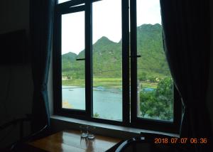 a window with a view of a river and mountains at Son Doong Riverside in Phong Nha