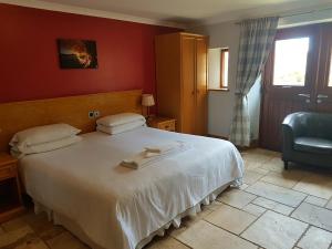 a bedroom with a white bed and a blue chair at King's Head Inn in Llangennith
