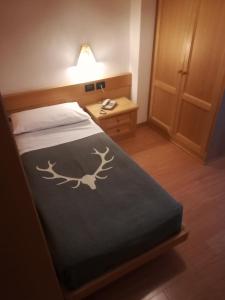 Un dormitorio con una cama con una estampa de ciervo. en Dolomiten Hotel Irma, en Canazei
