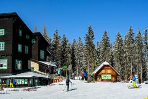 eine Gruppe von Menschen, die im Schnee neben einer Lodge Ski fahren in der Unterkunft Gasthof zum Jägerwirt in Mariazell