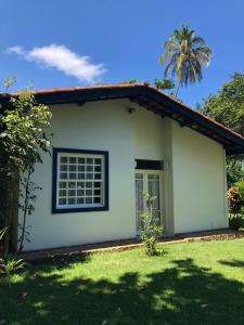 una pequeña casa blanca con una palmera en Casa Praia da Vila, en Ilhabela