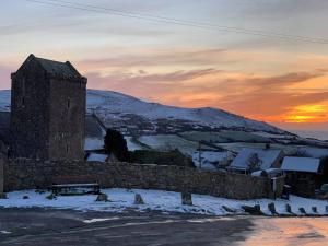 a building in the snow with the sunset in the background at King's Head Inn in Llangennith