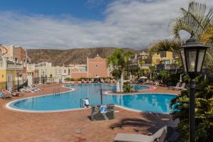 a large swimming pool with palm trees and buildings at Luxe Appartement Palm Mar in Palm-Mar