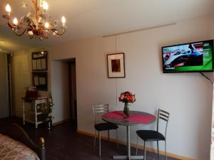 uma sala de estar com uma mesa e uma televisão na parede em Gîte à la campagne proche d'Angers et de la Loire em Saint-Martin-du-Fouilloux