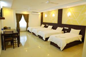 a hotel room with four beds and a table and a desk at Anna Residency in Nedumbassery