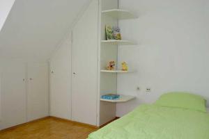 a bedroom with a green bed and white shelves at Haus Widenhorn in Sipplingen