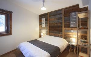 een slaapkamer met een bed met een houten muur bij Odalys Chalet De Louis in L'Alpe-d'Huez