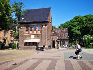 a woman walking in front of a brick building at Het Polderhuis in Den Burg