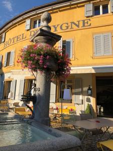 a fountain with flowers in front of a hotel at Hôtel du Cygne in Bevaix