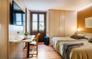 a hotel room with two beds and a desk and a table at Hotel Els Caçadors de Ribes in Ribes de Freser