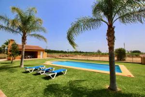 a pool with two palm trees and two lounge chairs at Finca las Ranas by CARLOSFERIEN in Denia