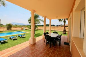 a patio with a table and chairs and a pool at Finca las Ranas by CARLOSFERIEN in Denia