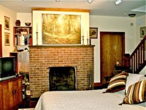 Whistler's Inn في لينوكس: غرفة نوم مع موقد مع لوحة على الحائط
