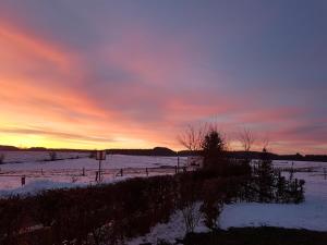 a snowy field with a sunset in the background at B&B La Chabetaine in Morhet